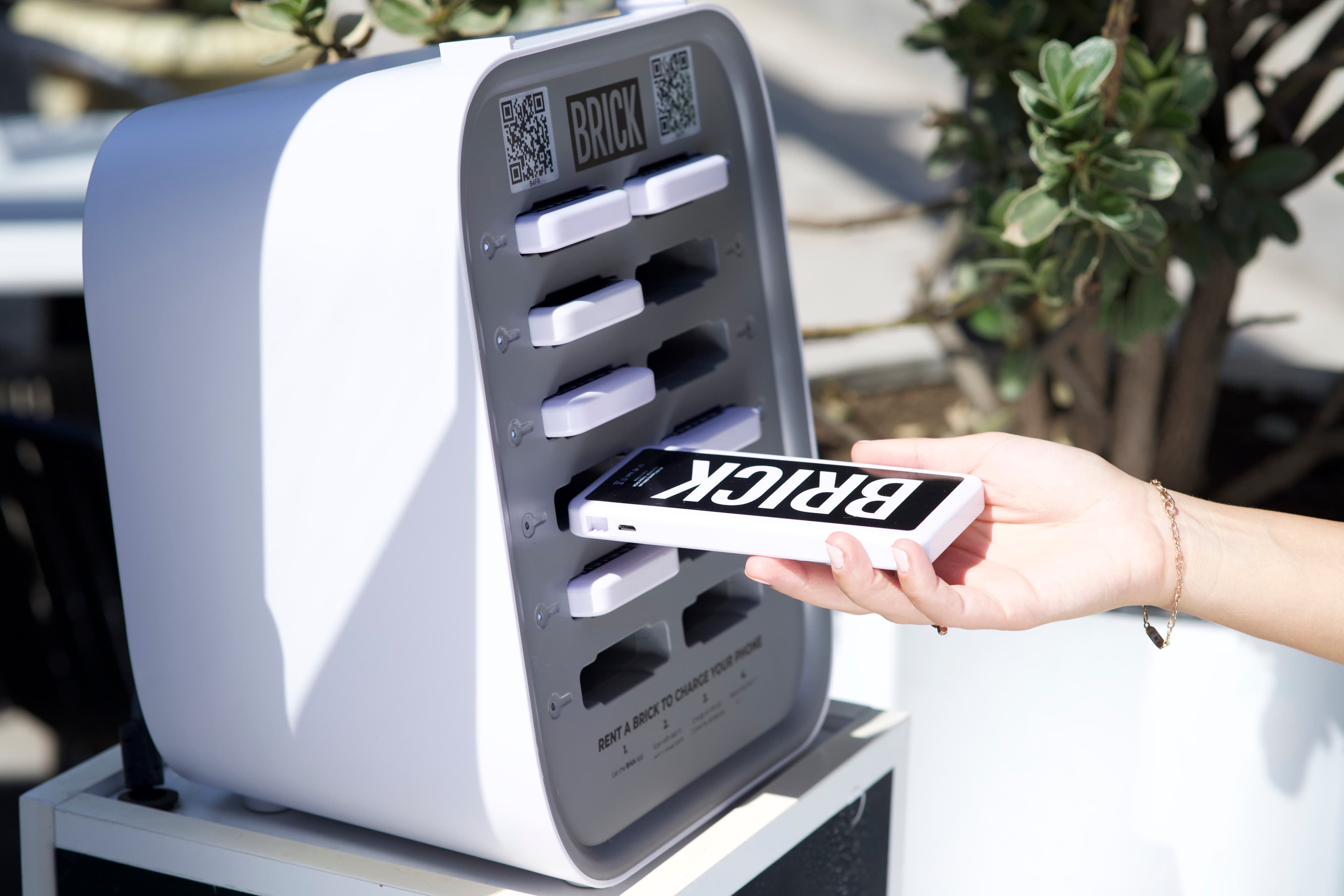 En hand som sätter in en Brick power bank i en station